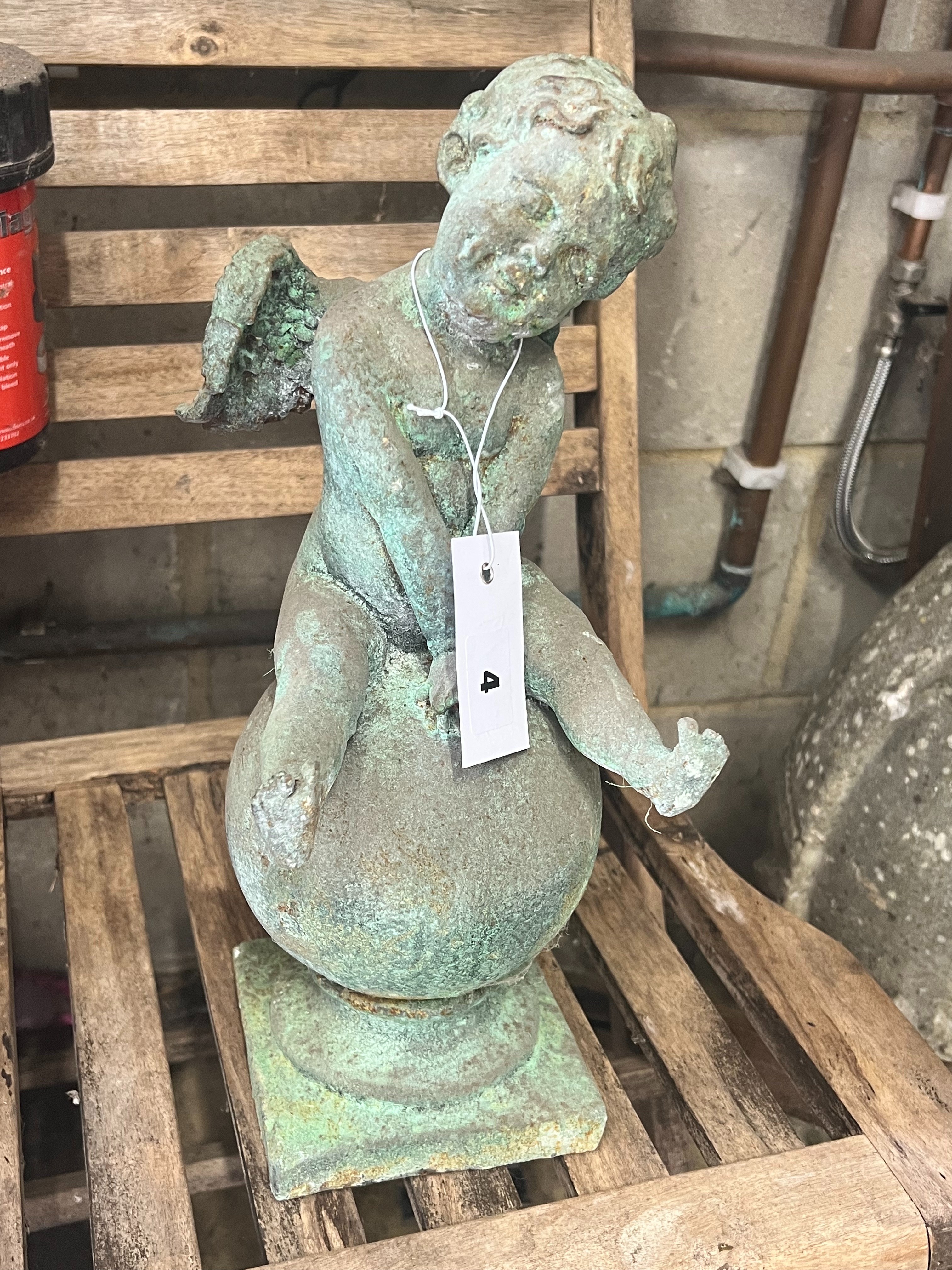 A cast iron cherub and orb garden ornament, height 38cm